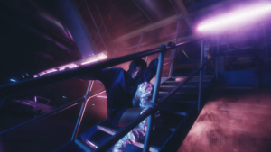 guy on stairs in a dark purple lit room